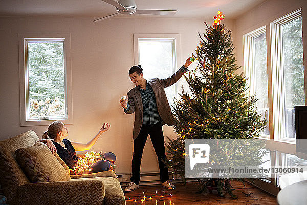 Man and woman decorating Christmas tree at home