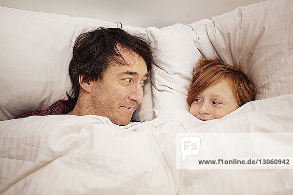 Father and son lying on bed at home