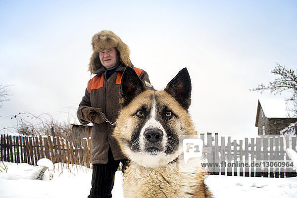 Portrait of man and dog on snow covered field