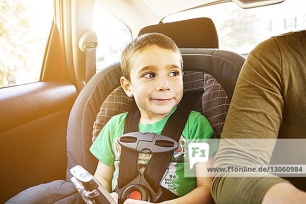 Lächelnder Junge sitzt an einem sonnigen Tag im Autositz
