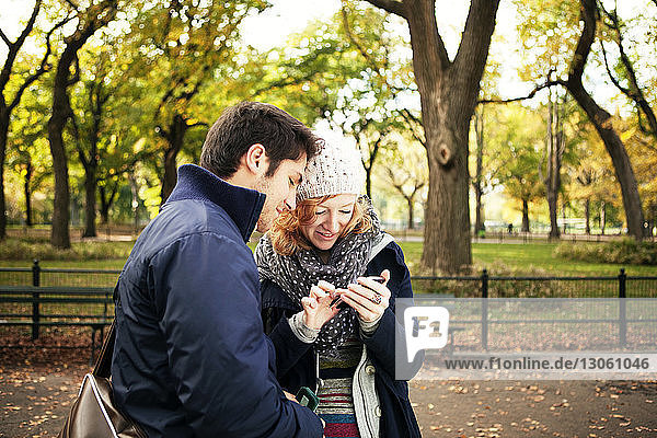 Young couple using phone while standing in Central Park