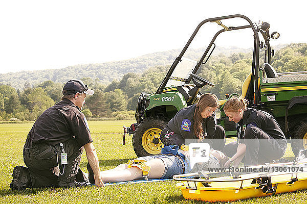 Rettungskräfte heben Patienten mit Sanitätswagen auf Grasfeld
