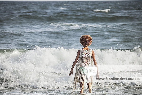 Rear view of girl standing in sea on sunny day