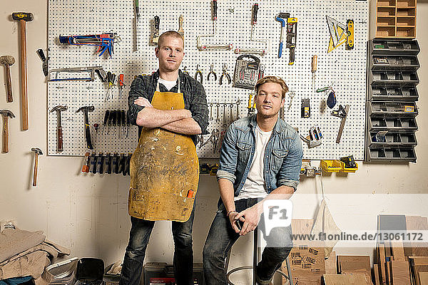 Portrait of male carpenters against wall with tools in workshop
