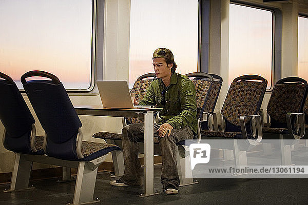 Man using laptop computer while traveling in ship