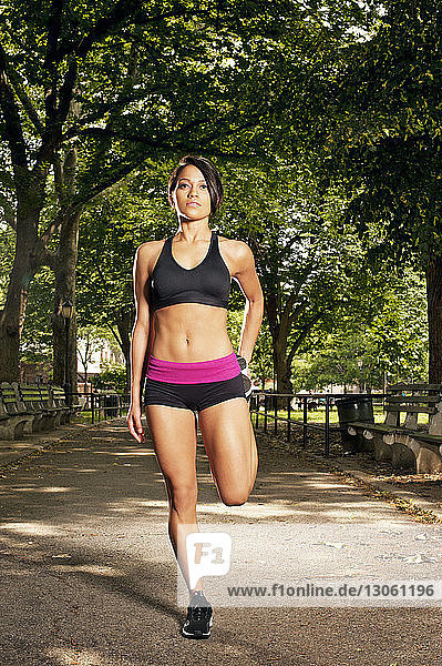 Entschlossene sportliche Frau trainiert auf Fußweg im Park