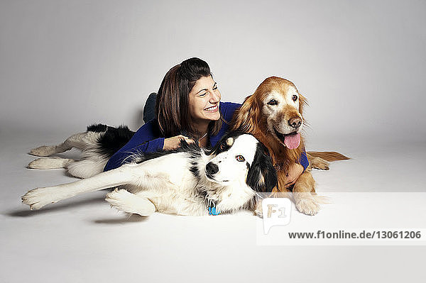 Happy woman lying with dogs on white background