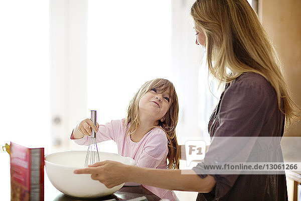 Cute girl looking at mother while baking at home
