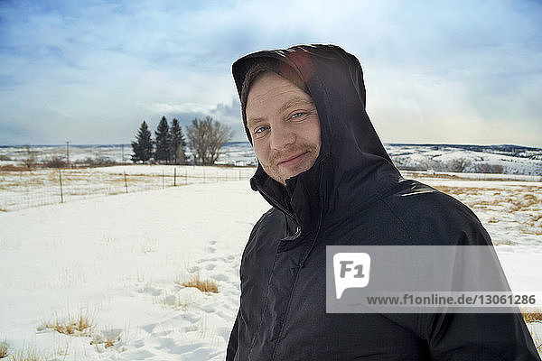 Portrait of man standing on snowy field against sky