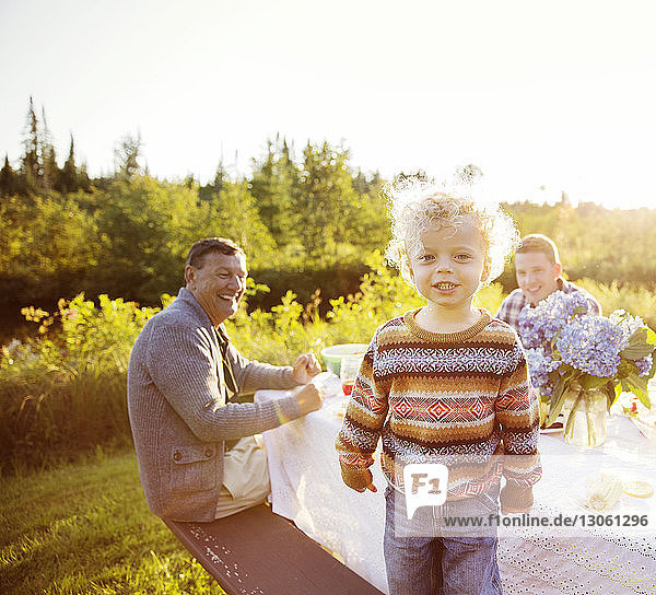 Porträt eines Jungen  der sich mit der Familie auf einem Picknicktisch vergnügt