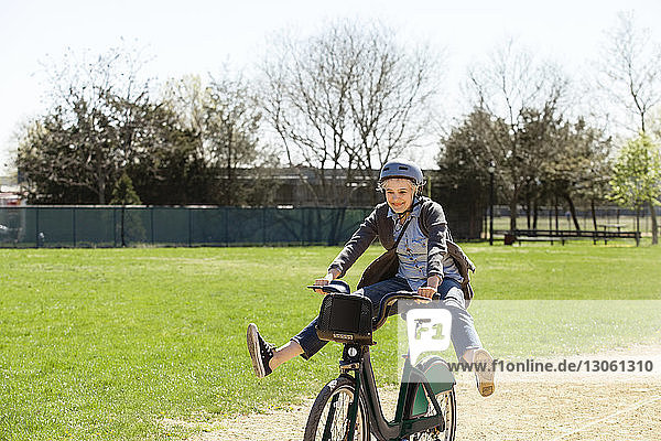 Cheerful woman playing while riding bicycle at park
