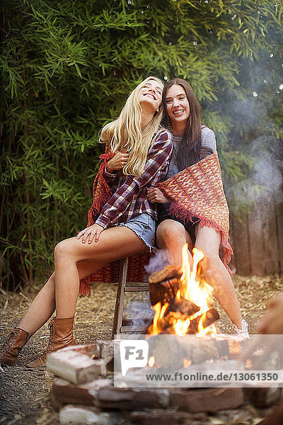Glückliche Freunde sitzen auf einem Hocker am Lagerfeuer