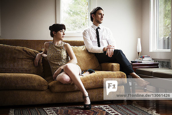 Ehepaar schaut weg  während es zu Hause auf dem Sofa sitzt
