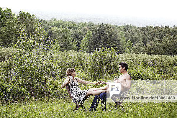 Paar  das im Feld auf einem Stuhl sitzend Händchen hält