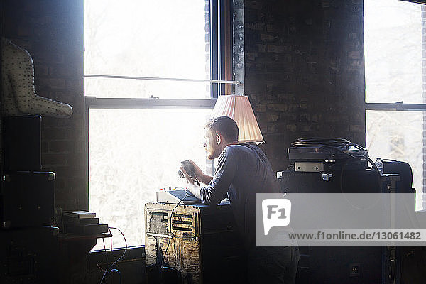 Man with camera standing by window at home