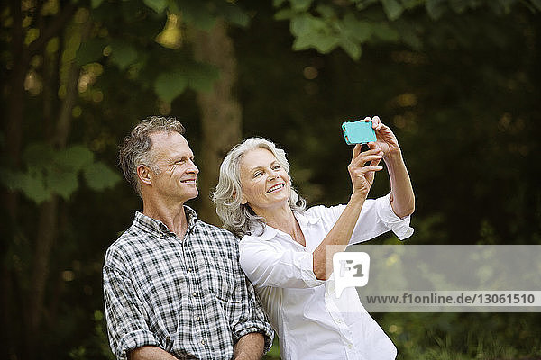 Happy senior couple taking selfie in forest