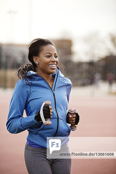 Smiling woman exercising with dumbbells on playing field