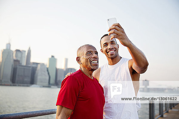 Glücklicher Mann nimmt sich mit seinem Vater am East River in die Stadt