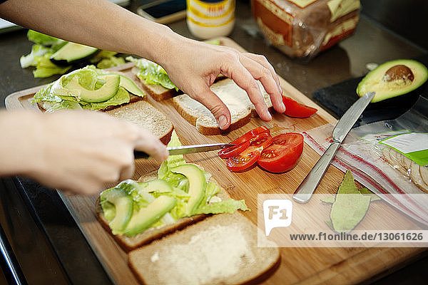 Beschnittenes Bild eines Mannes  der in der Küche ein Sandwich zubereitet
