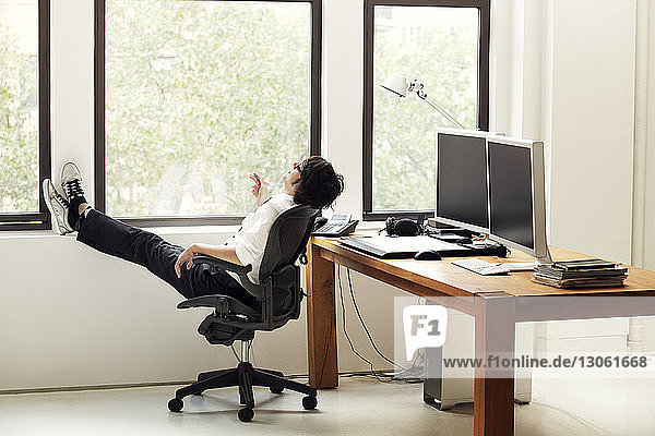 Seitenansicht eines Geschäftsmannes  der sich im Büro auf einem Stuhl entspannt