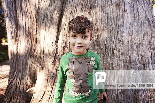 Porträt eines süßen Jungen an einem Baumstamm stehend