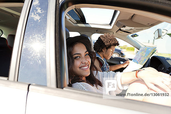 Porträt einer glücklichen Frau mit Freundin  die im Auto reist