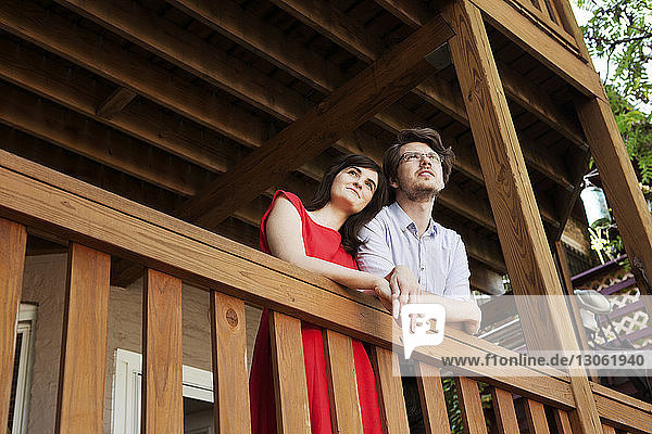Low angle view of young couple standing at railing in balcony