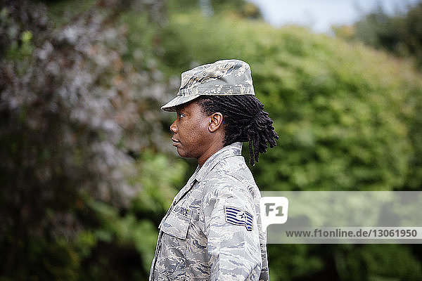 Profile view of female soldier standing against trees