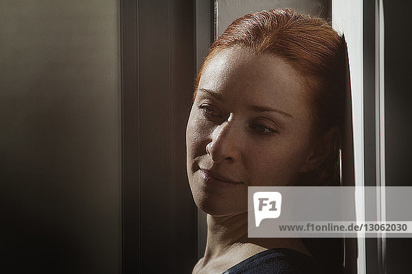 Close-up of woman looking away while leaning on wall at home