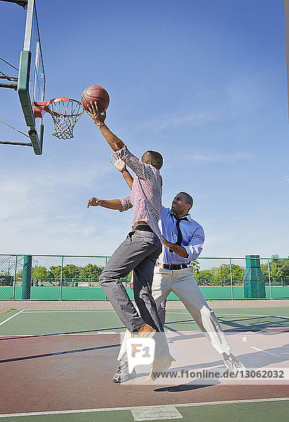 Männer spielen an sonnigen Tagen Basketball auf dem Platz