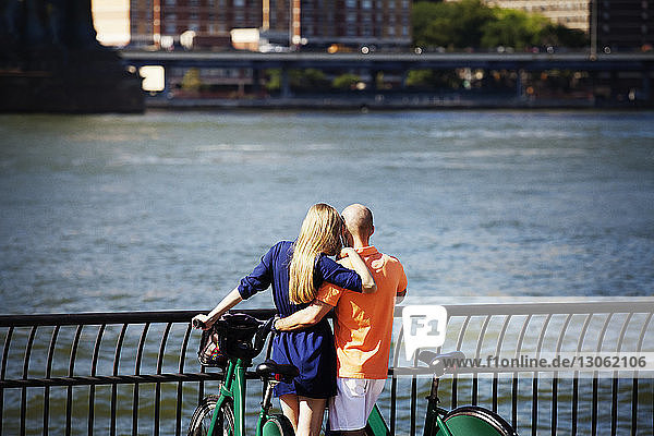Rückansicht eines Paares mit Fahrrädern  das am Ostfluss steht