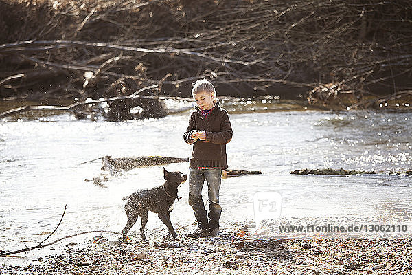 Boy standing with dog by river