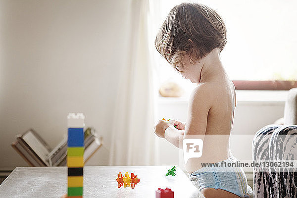 Seitenansicht eines Mädchens  das zu Hause mit Spielzeugklötzen spielt