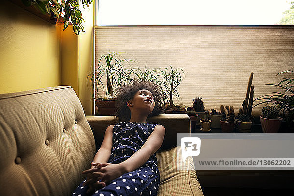 Girl looking away while relaxing on sofa at home