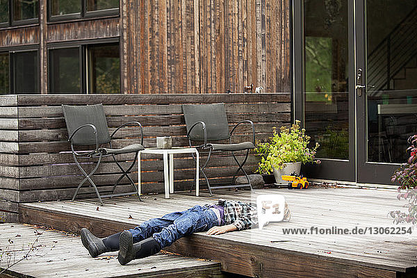 Boy lying down on porch outside house