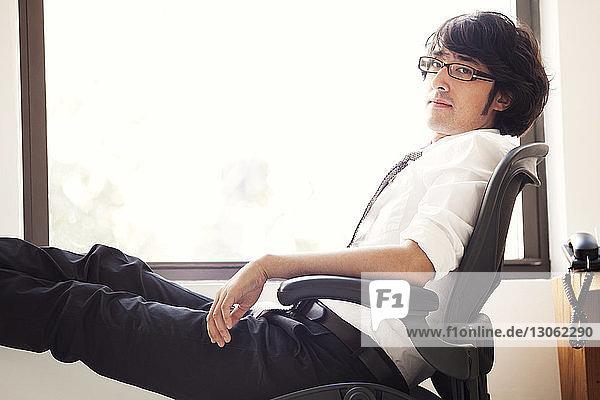 Porträt eines Geschäftsmannes  der sich im Büro auf einem Stuhl entspannt