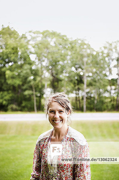 Porträt einer glücklichen Frau  die auf einem Feld im Park steht