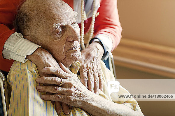 Frau im Mittelteil mit Händen auf der Schulter eines älteren Mannes