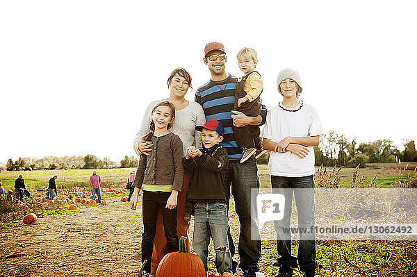 Happy family standing at farm against clear sky