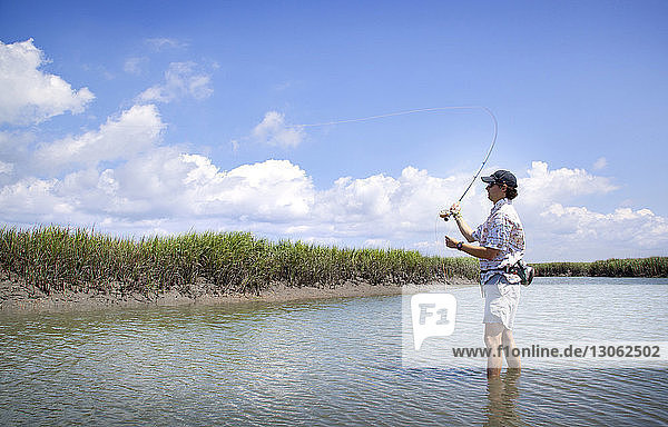 Mann fischt im See gegen den Himmel