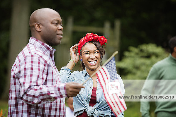Glückliche Frau schaut auf Mann mit amerikanischer Flagge im Hinterhof