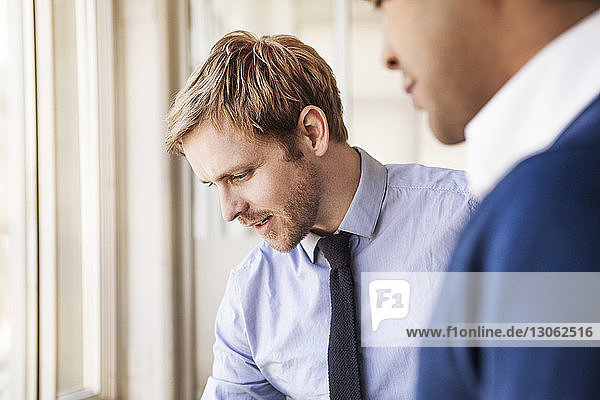 Close-up of businessman standing by coworker at office