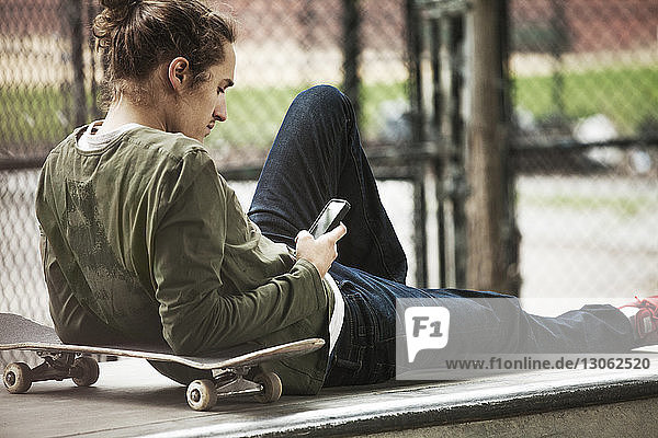 Mann benutzt Smartphone  während er sich auf einem Sitz im Skateboard-Park entspannt