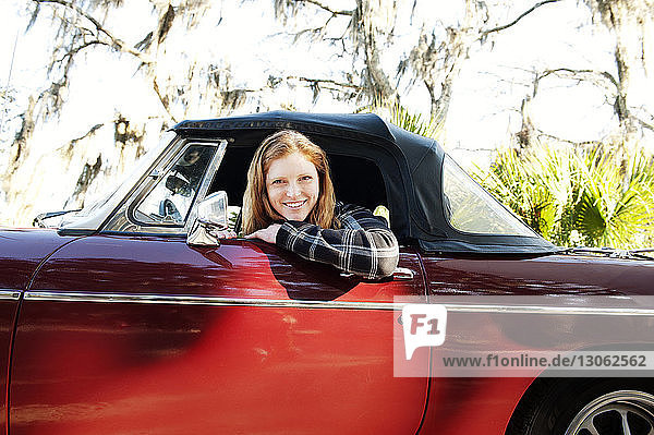 Portrait of happy woman sitting in convertible car