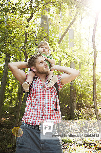 Vater trägt Sohn auf den Schultern  während er im Wald steht
