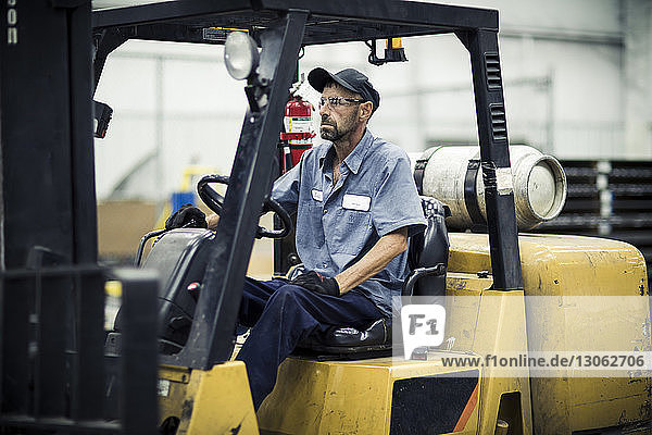 Serious manual worker sitting in forklift at metal industry