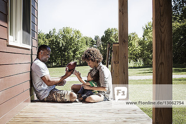 Vater und Kinder mit Fussball auf der Veranda sitzend