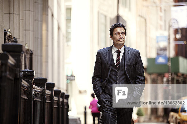 Confident businessman walking on city street