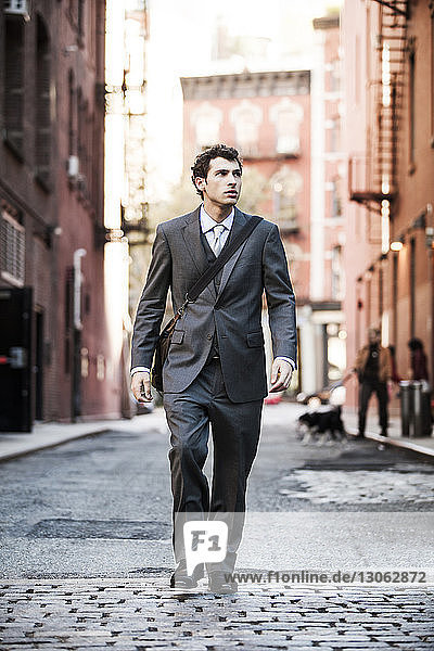 Businessman walking on street amidst buildings