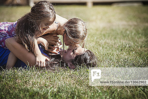 Töchter spielen mit der Mutter auf dem Rasen